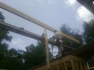 Carpenter setting a ridge beam over a new addition frame — Ice Dam Removal by Roofing Brothers in Branchdale