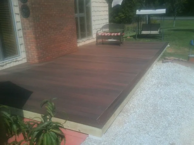 Freshly stained wood deck built against a brick home in Branchdale