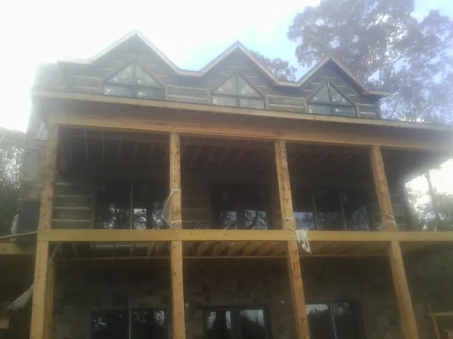 Dormers and porch framing on a large log home under construction — Roof Coating work by our crew in Branchdale