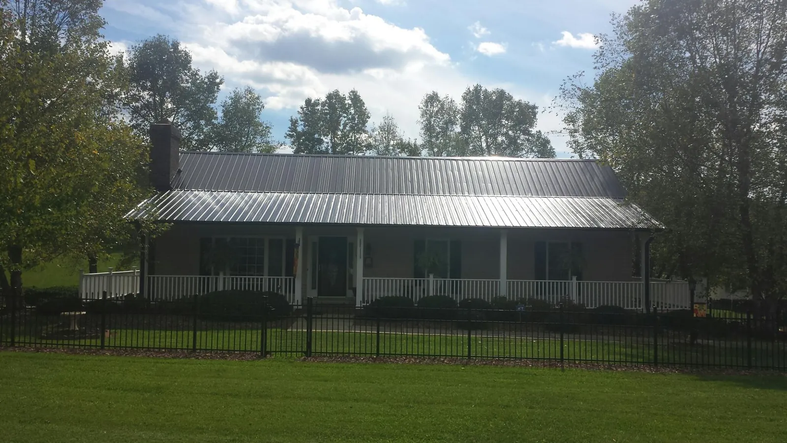 Gray metal roof on a brick ranch with a full width front porch — Gutter Guard Installation work by our crew in Branchdale