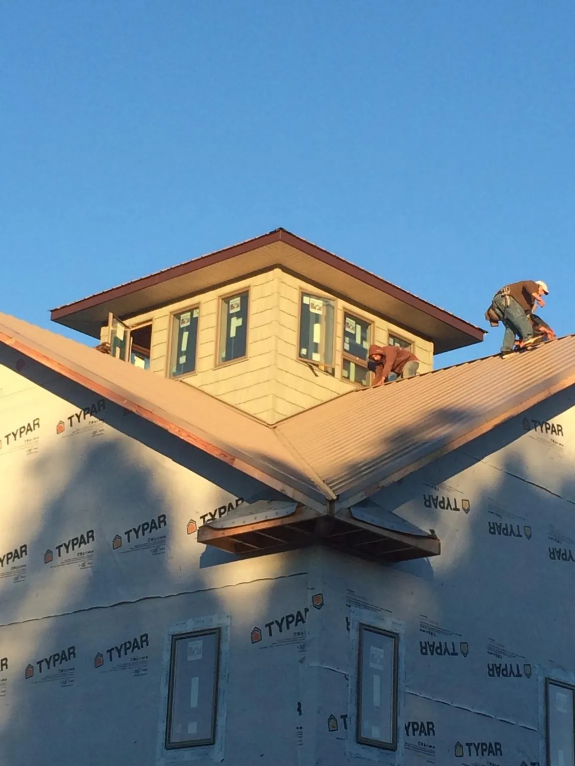 Roofers working around a rooftop cupola on a new metal roof at sunset — Roof Waterproofing in Branchdale by Roofing Brothers
